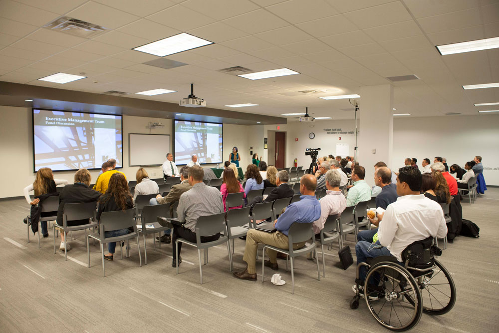 Training room with a large group, interacting in a panel discussion.