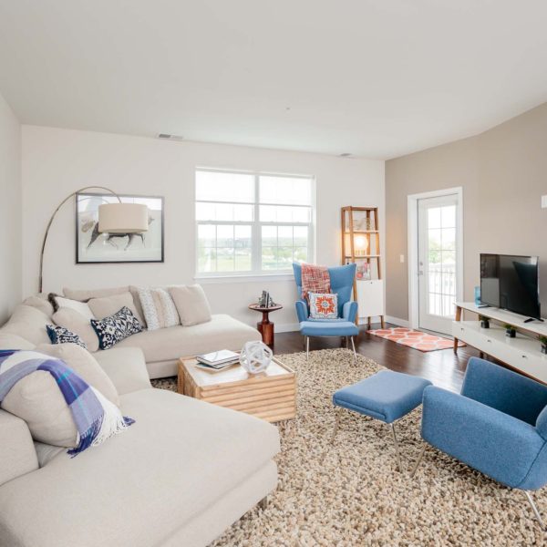 Family room with a white couch, blue chairs and a t.v.