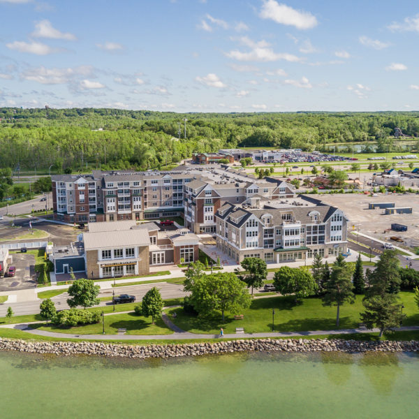 Aerial of multi-unit builidngs and storefronts on the shore line of a lake.