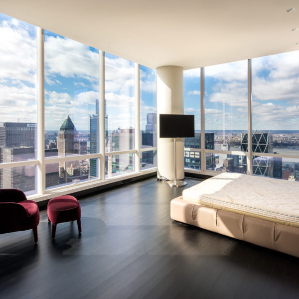 Penthouse bedroom with chair and bed overlooking city skyline.