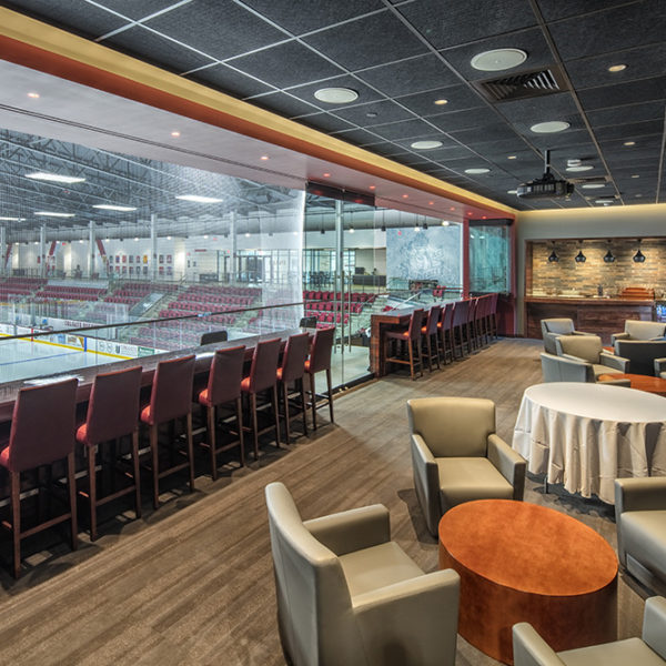 VIP box with a row of seats at the glass and tables and chairs for lounging