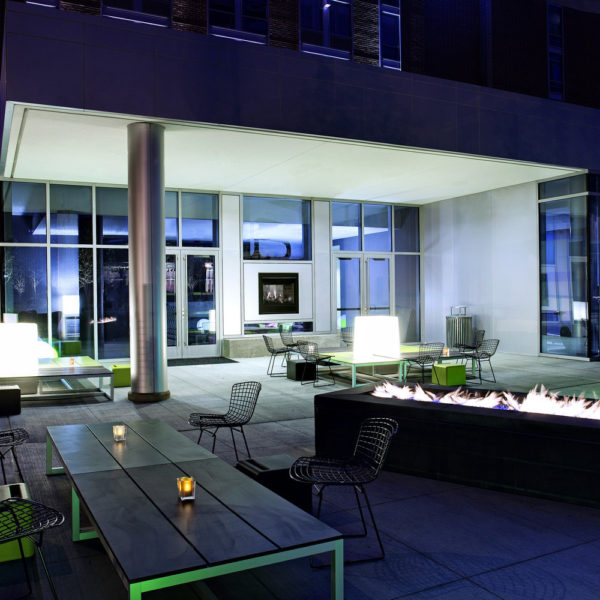 Outdoor patio at night with tables, chairs and fire pit