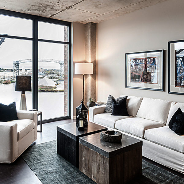 Apartment living room with couches and coffee table overlooking river.