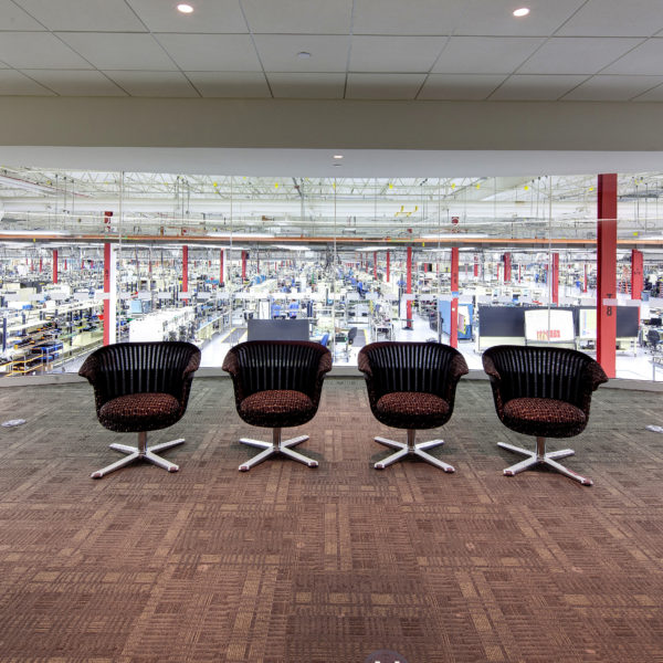 Four chairs overlooking glass wall into manufacturing space