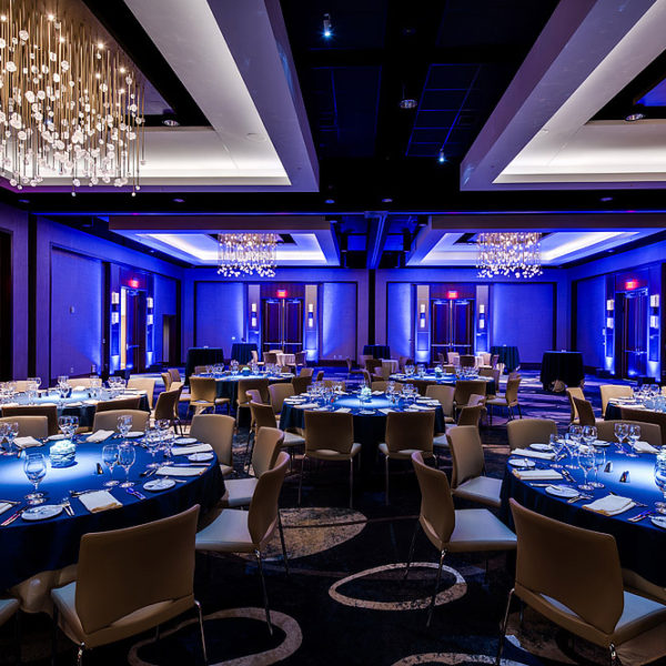 Banquet room with tables and chairs with blue back lit lighting.