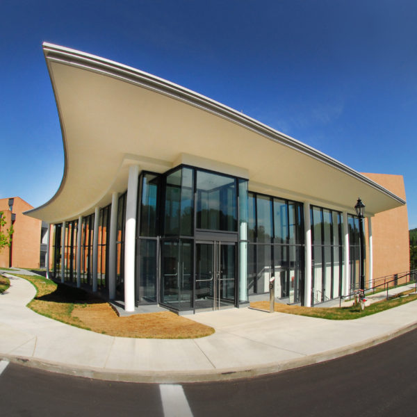 Corner of building showing glass facade and entrance with blue sky in the background.