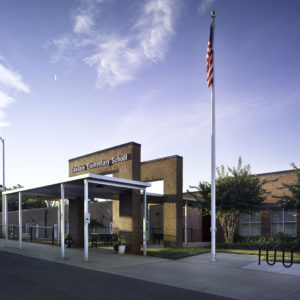 Exterior of school with American flag and blue sky.