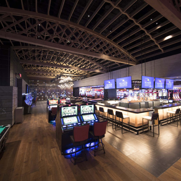 Casino bar with tv screens, gaming machines and exposed wooden tresses.