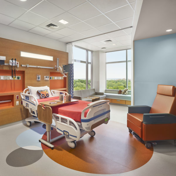 Colorful paitnet room with hospital bed and chair.