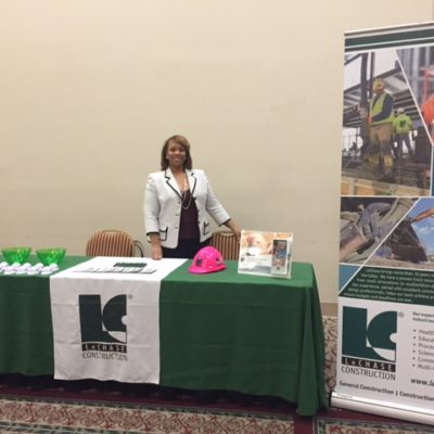 Women standing behind LeChase table with pull up banner at a conference.